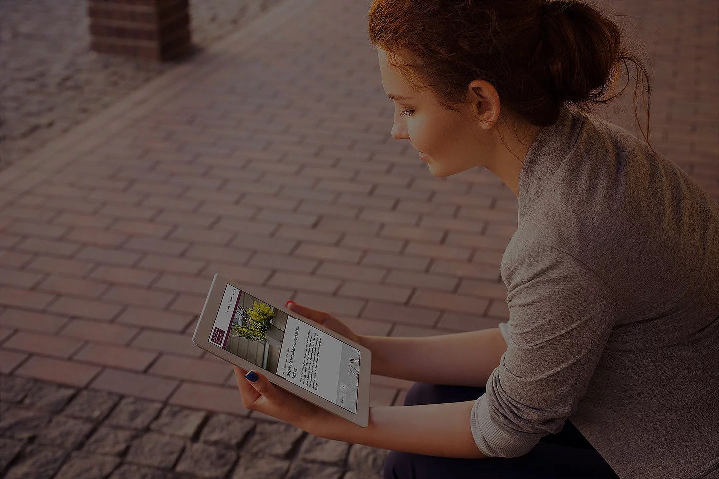 Frau liest auf einen Tablet die Webseiten des Gedenkbuch Augsburg